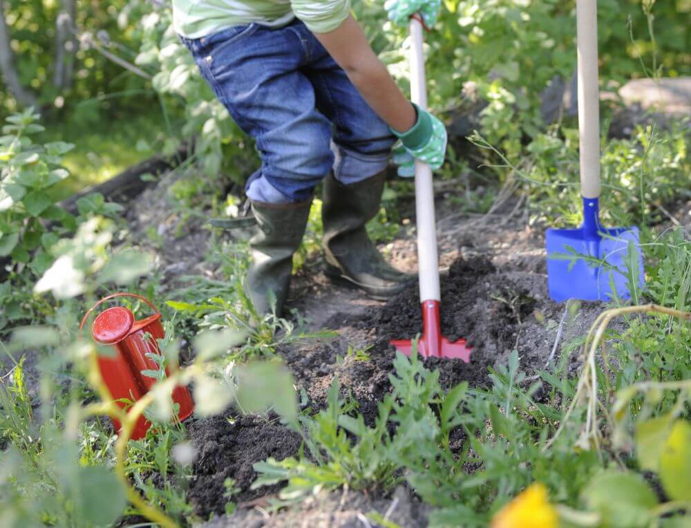 Child working in the garden with spades and watering can from Gluckskafer toys