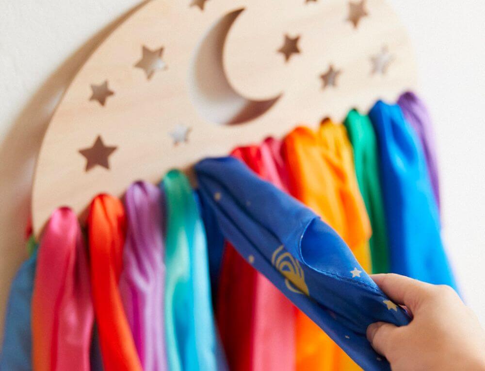 Child grabbing one of a selection of colourful Sarah's Silks  playsilks from a wooden organiser 
