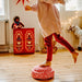 Child playing with a red and white blush limited edition original on a wooden floor, surrounded by toys and decorations.
